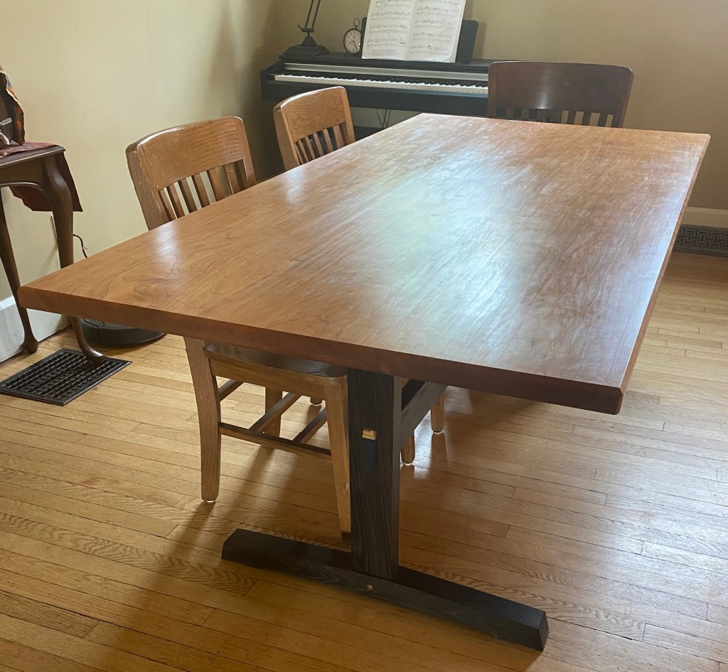 Completed cherry and white oak trestle dining table with ebonized oak base and natural cherry top