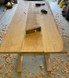 Cherry table top mid-flattening process showing glued boards being planed with Japanese hand plane