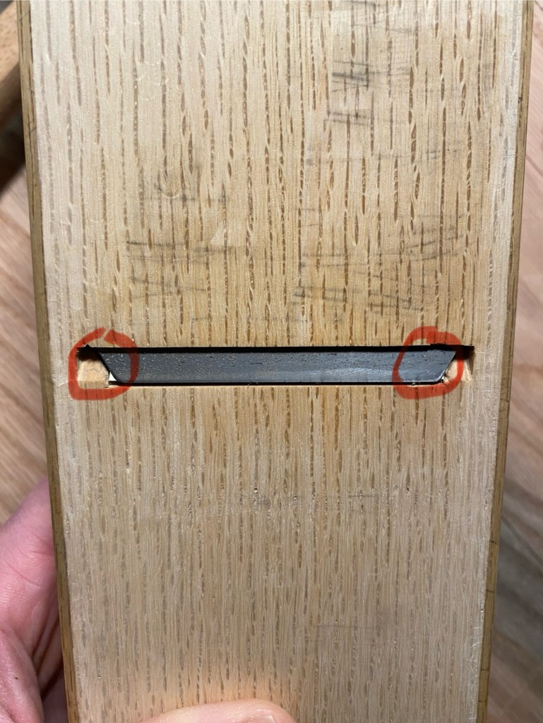 Bottom view of Japanese plane showing chipbreaker corners with ground-back blade ears, red circles indicate chipbreaker position relative to cutting edge